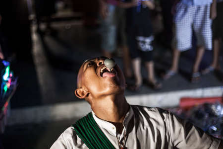 YANGON, MYANMAR DECEMBER 3, 2016 : Street performer in Maha Bandula Park with spinning top performs for crowd at nightのeditorial素材