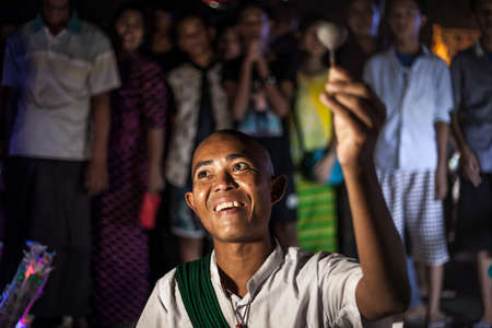 YANGON, MYANMAR DECEMBER 3, 2016 : Street performer in Maha Bandula Park with spinning top performs for crowd at nightのeditorial素材