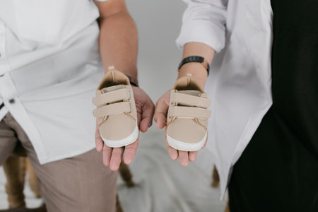 cropped shot of pregnant woman and husband holding baby shoes isolated on greyの写真素材