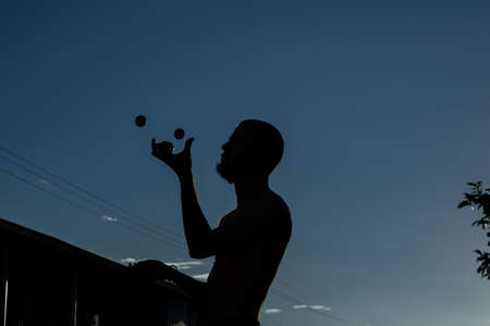 Person life style scene, Man doing juggles with balls and blue sky backgoundの写真素材