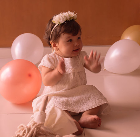 Little one year girl baby with balones and dolly