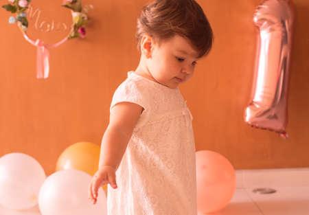 Little one year girl baby with balones and dollyの写真素材