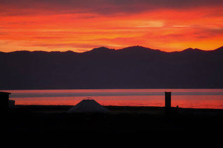 A stunning sunset paints the sky in vibrant shades of orange and red, reflecting off the calm waters of a lake.の写真素材