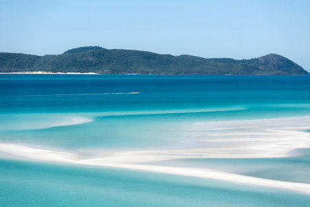 This image captures a pristine beach with white sandy shores merging into the clear turquoise waters of the ocean.の写真素材