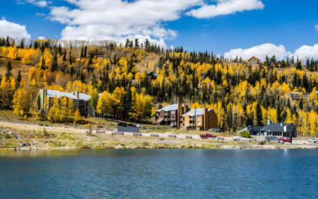 Vibrant autumn foliage surrounds a tranquil lakefront community, with colorful trees and clear blue skies reflecting in the calm waters.の写真素材