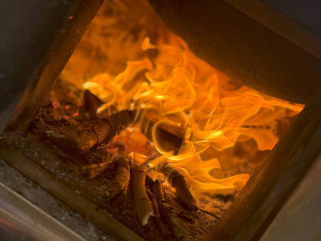 A close-up of firewood burning in a fireplace, with bright orange flames consuming the wood.の写真素材