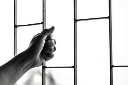 Hand of the prisoner in a steel lattice ,black and whiteの写真素材