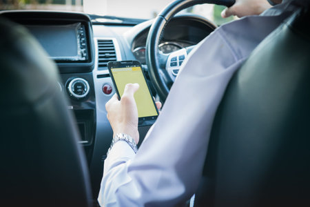 Businessman touching and using smartphone for online chat In front of steering wheel at Front seat in car interior,using navigation on smartphone,smart technology conceptsの写真素材