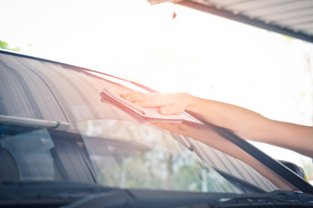 Worker cleaning  car with microfiber cloth, car detailing selective focus concept.