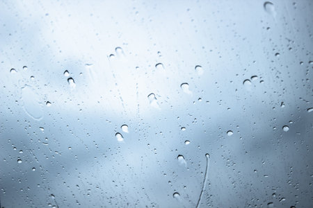 Rain drops on window glasses surface with cloudy background , natural pattern of raindrops isolated...