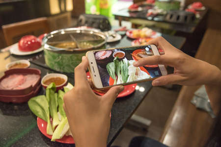 Teenagers hands taking picture of food by mobile phoneの写真素材