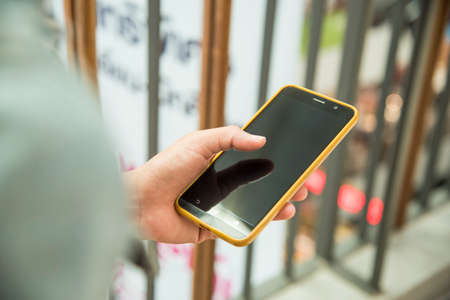 Male hand holding a phone on a shopping mallの写真素材