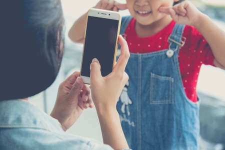 Woman holding smartphone photographing a child in the shopping mallの写真素材