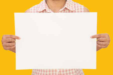 Woman showing white big A3 paper on yellow backgroundの写真素材