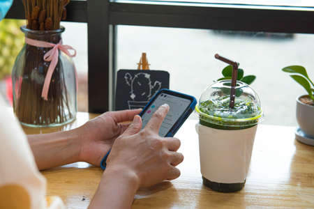 Woman hand holding and use credit card to payment drinks in cafe shop,online shopping from home , payment e-commerceの写真素材