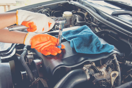 Hands of mechanic repairing the engine of the special keys .Professional car mechanic in gloves working , field service.の写真素材