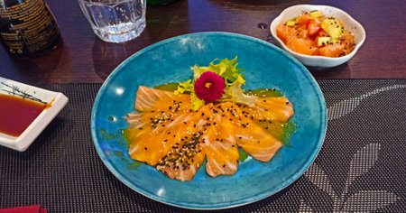 Salmon sashimi on a blue plate in a Japanese restaurantの写真素材
