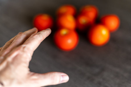 Man's hand ready to pick one or several tomatoes on the kitchen table