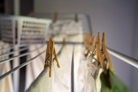 Washed clothes hanging with clothespins on a folding clothesline inside a house next to the warmth...