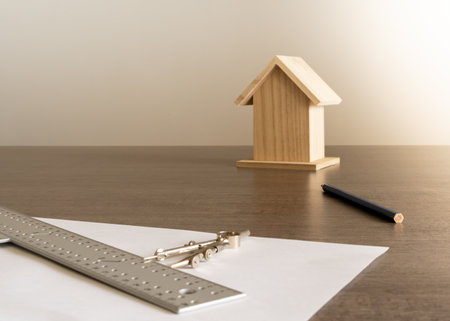 Objects on the table in an architect's office with a small wooden house in the background for decoration.の写真素材