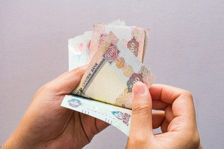 Closeup of a female's hands counting UAE 500 dirhams currency notes, paper money against a light backgroundの写真素材
