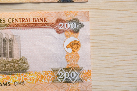 Closeup of UAE 200 dirhams currency notes on light wooden table from high angle, paper moneyの写真素材