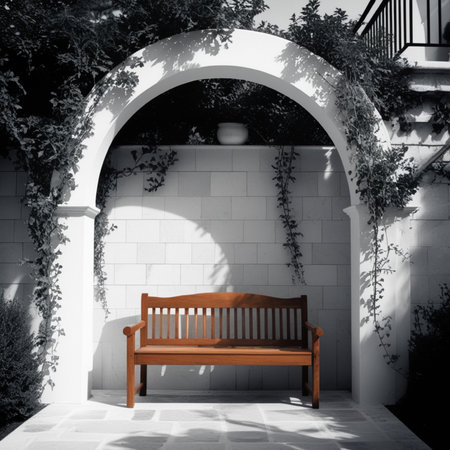 Wooden bench under the arch of the white wall in the gardenの写真素材