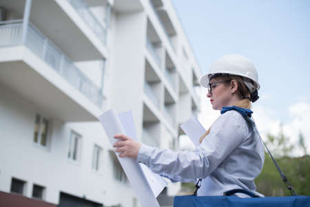 woman engineer in front of building looking at blueprintsの写真素材