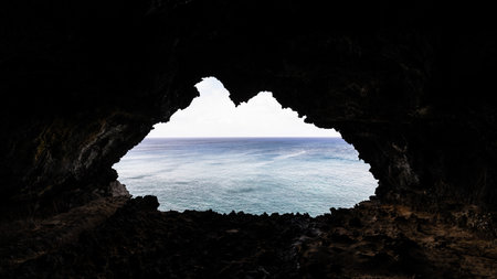 The Ana Kakenga lava tunnel with an exit hole over the blue ocean of the Pacific on the coast of Rapa Nui, Easter Island.の写真素材