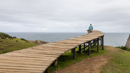A person on the Muelle De Las Almas jetty on Chiloe, which leads into the ocean at the end of the world.の写真素材