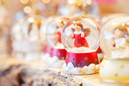 A row of Christmas snow globes on an outdoor table with focus on an angelの写真素材