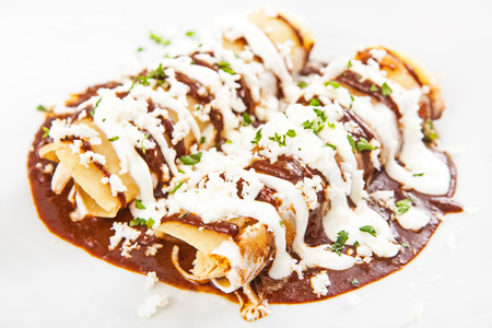 Plate of two delicious Mexican chicken enchiladas with mole sauce and melted cheeseの写真素材