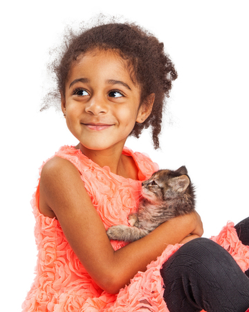 Happy mixed race four year old girl holding a kitten and looking up with a smileの写真素材