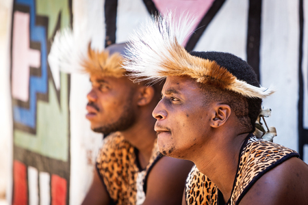 LESEDI CULTURAL VILLAGE, SOUTH AFRICA - NOVEMBER 4, 2016. Two young male Zulu tribe members wearing traditional warrior leopard skin garments and headdressesのeditorial素材