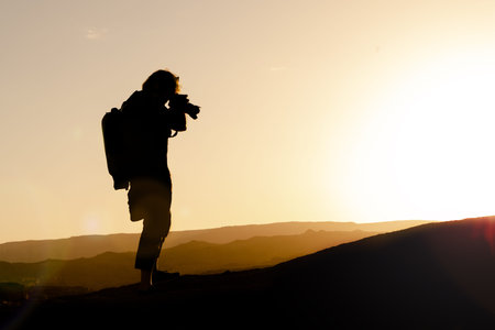 Silhouette of a professional travel photographer taking photos of a mountainscape in Arizona at...