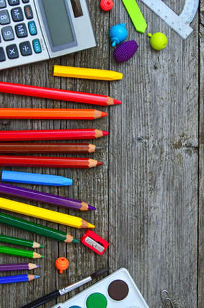 Stationary, calculator, crayons, water colors and color pencils on wooden tableの写真素材