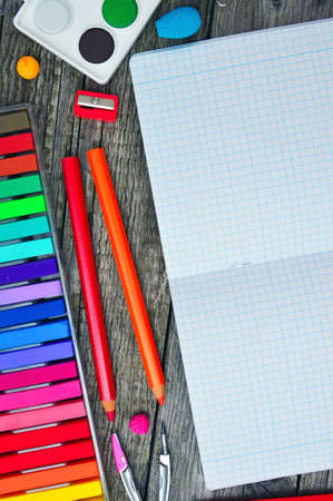 Stationary, crayons, water colors, color pencils and exercise book on wooden tableの写真素材