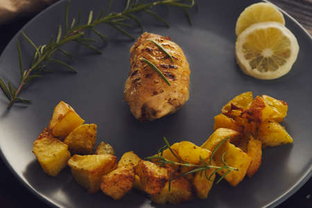 A chiken roll roasted on a gray plate with baked potatoes. low key style.の写真素材