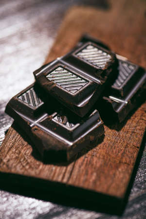 dark chocolate tabs on a small chopping board on a wooden tableの写真素材
