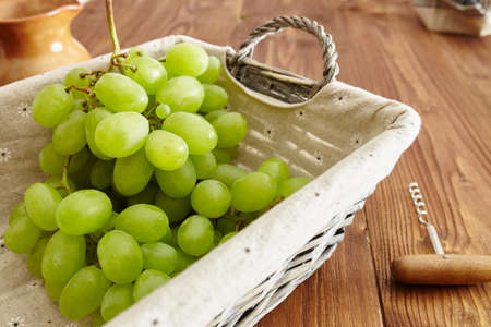 grapes in a basket on an old wooden tableの写真素材