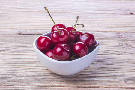 fresh cherries in a dish on the wooden deskの写真素材