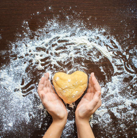Woman's hands made from the dough heart. The symbols of protection, warmth and comfort. Baking lovers on Valentine's Dayの写真素材
