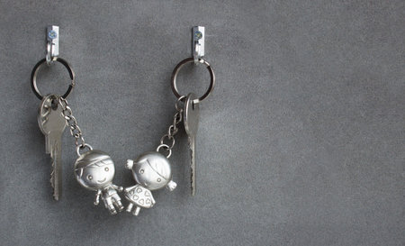 Keyrings boy and girl pulling hands. Lovers keychains, love. Gray background