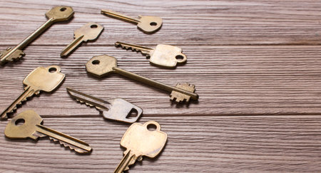 Older different golden keys on a wooden tableの写真素材