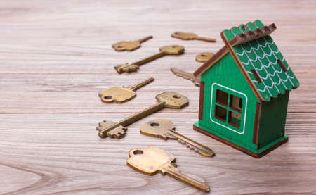 Home and golden keys on a wooden tableの写真素材