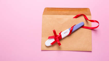 letter with a positive pregnancy test on a pink backgroundの写真素材