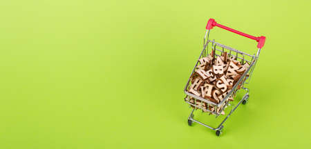 Shopping basket with letters of the alphabet made of wood on a green backgroundの写真素材