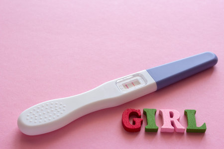 girl word from wooden letters, positive pregnancy test with two stripes on a pink backgroundの写真素材