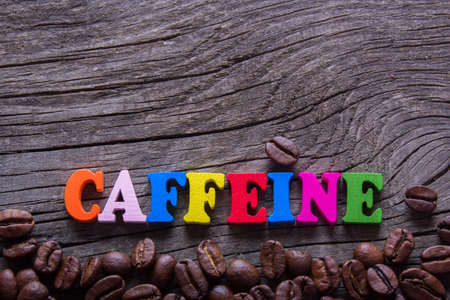 word caffeine and coffee beans on old wooden tableの写真素材