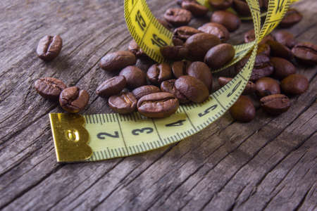 coffee beans and yellow measuring tape on an old wooden tableの写真素材